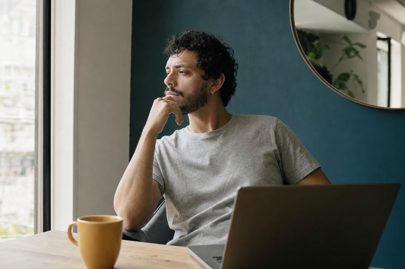 Desenvolvedor pensativo diante do notebook, no escritório de casa